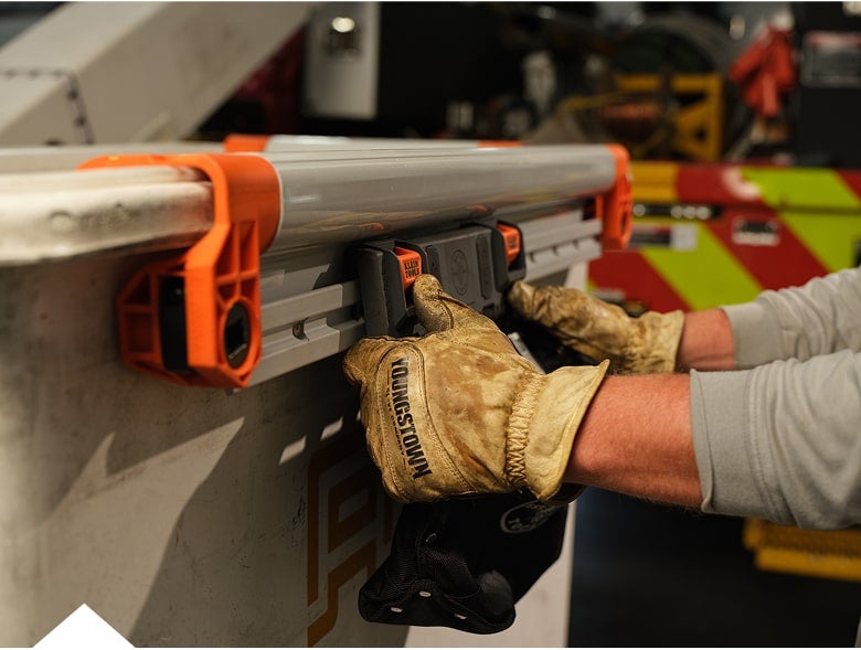 close up photo of a man installing a rail system module on the outside of a rail on a lineman bucket