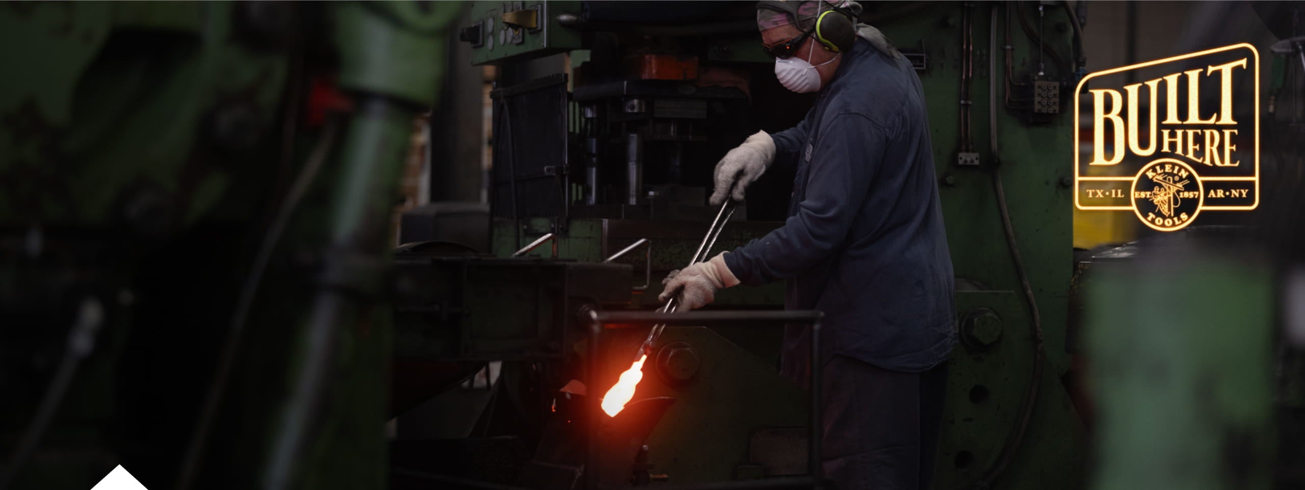 photo of worker holding a pair of pliers in a forge