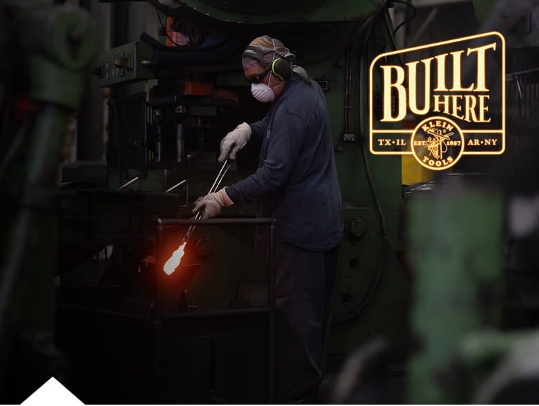 photo of worker holding a pair of pliers in a forge