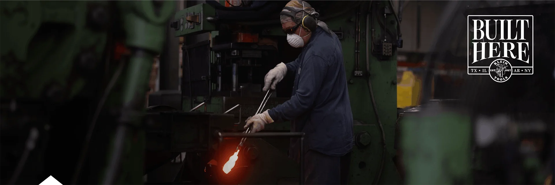 photo of worker holding a pair of pliers in a forge