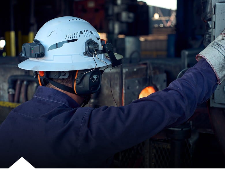 photo of a worker wearing a Klein Tools hart hat with the fan and earmuff accessories