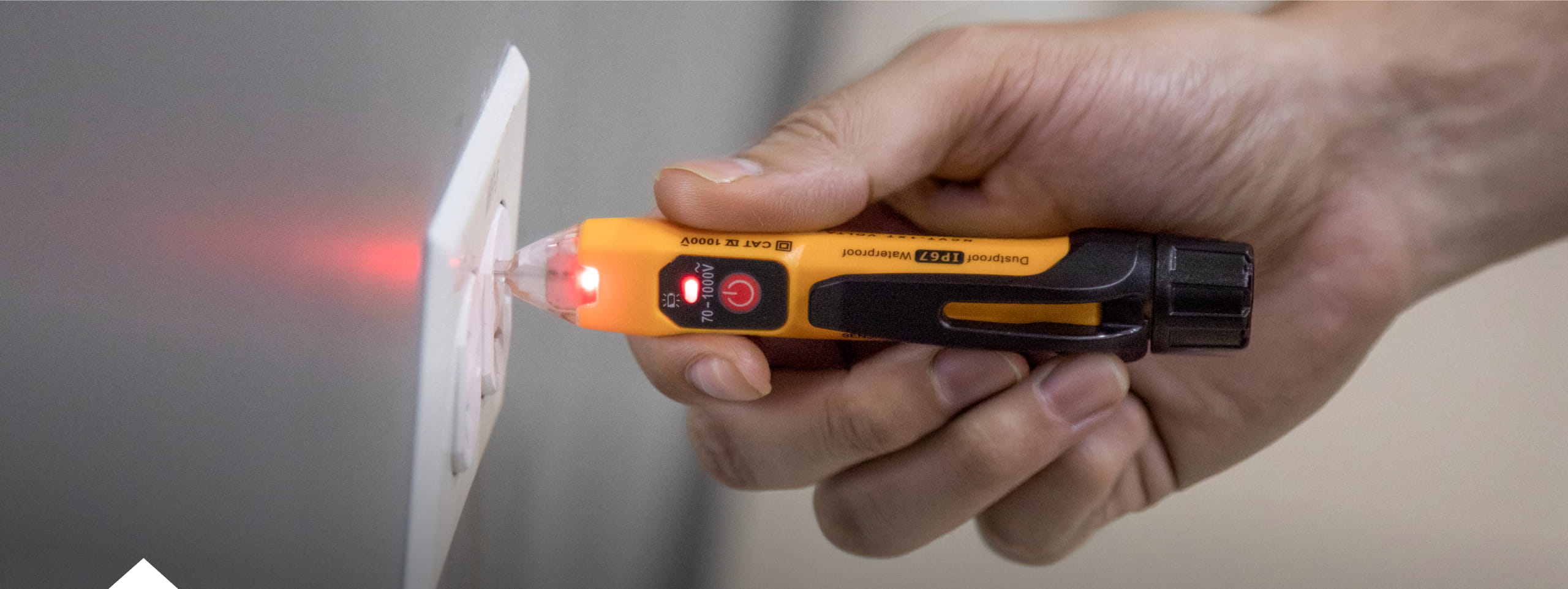 photo of a non-contact voltage tester in use testing an electrical outlet