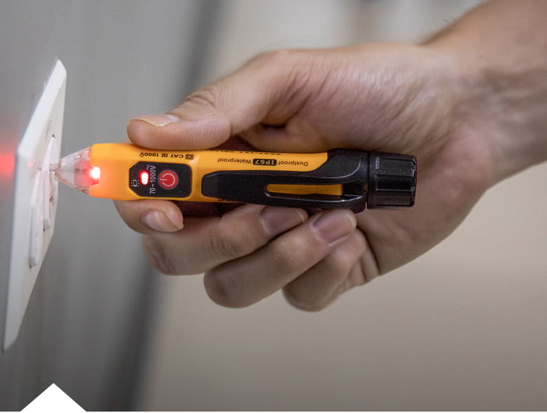 photo of a non-contact voltage tester in use testing an electrical outlet
